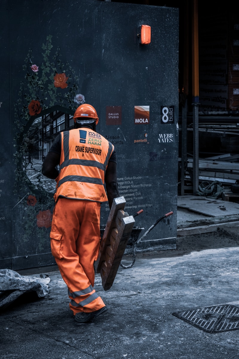 man in orange safety vest holding metal